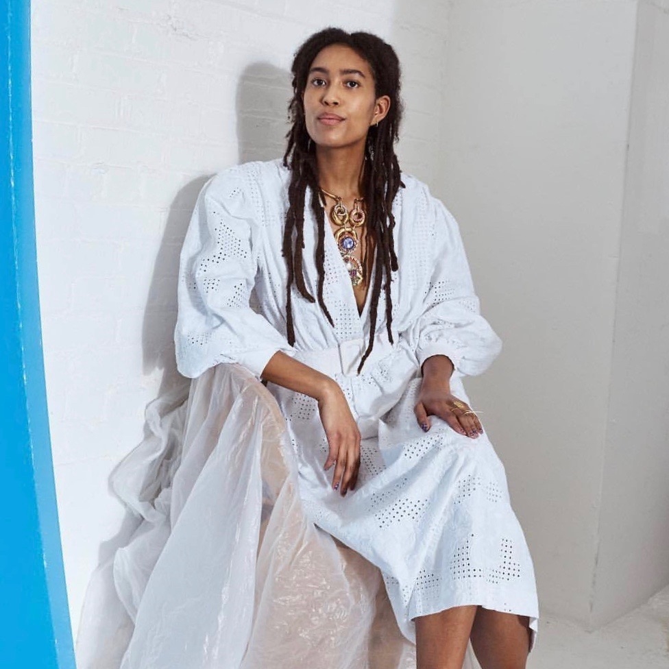 Sienna Fekete sits in a white dress against a white wall